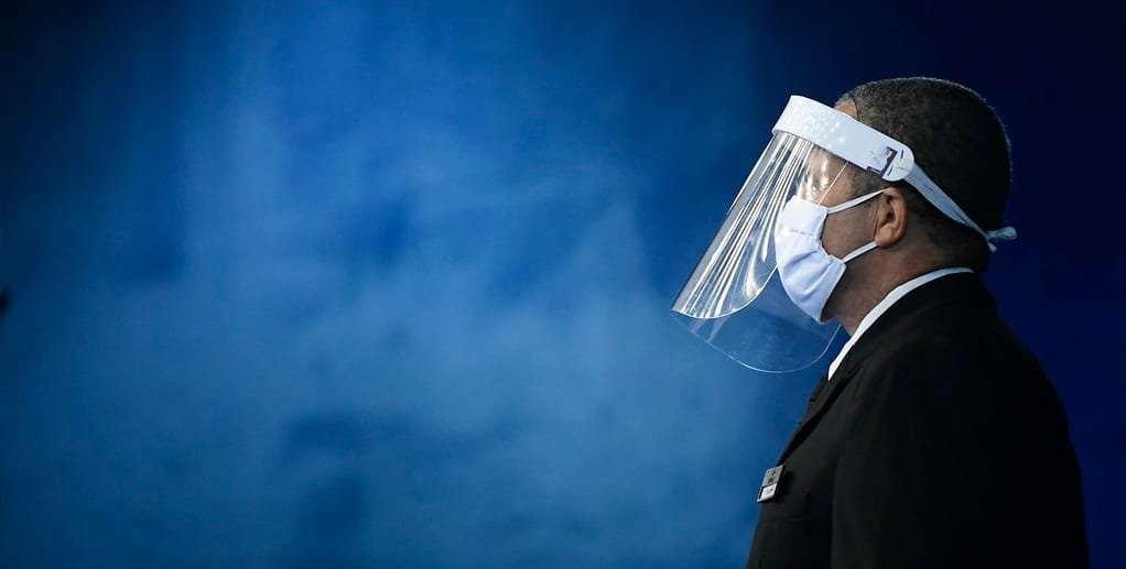 Servidor do Senado passa pelo plenário com o face shield, que é a proteção de plástico transparente para o rosto/Marcos Oliveira/Agência Senado