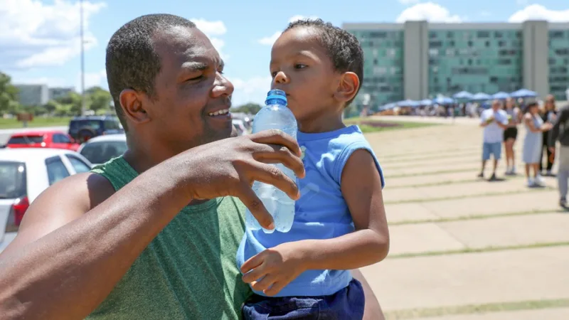 Turista hidrata o filho durante a visita que faz na Catedral Metropolitana, que passou também a ter um refiorço na segurança/Lúcio Bernardo Jr./Agência Brasília