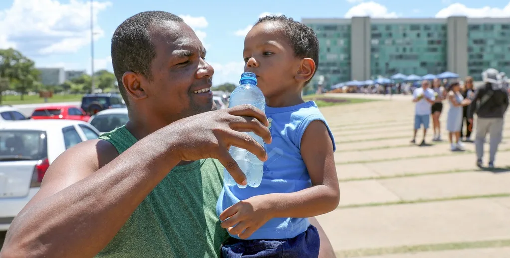 Turista hidrata o filho durante a visita que faz na Catedral Metropolitana, que passou também a ter um refiorço na segurança/Lúcio Bernardo Jr./Agência Brasília