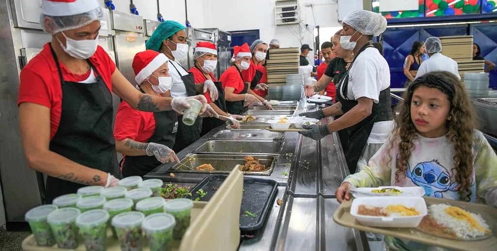 Menina leva a bandeira com prato de comida no Restaurante Comunitário do Itapoá, integrado à campanha Nosso Natal/André Feitosa/PCDF